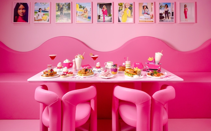 Pink-themed cafe table with assorted desserts and drinks at Barbie, The Dream Experience.