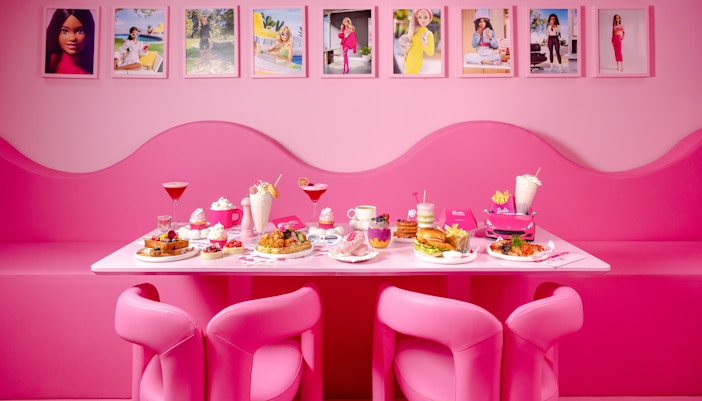 Pink-themed cafe table with assorted desserts and drinks at Barbie, The Dream Experience.