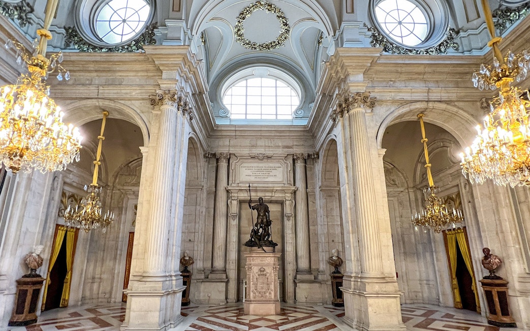 Hall of columns with chandeliers and statue, Royal Palace of Madrid.
