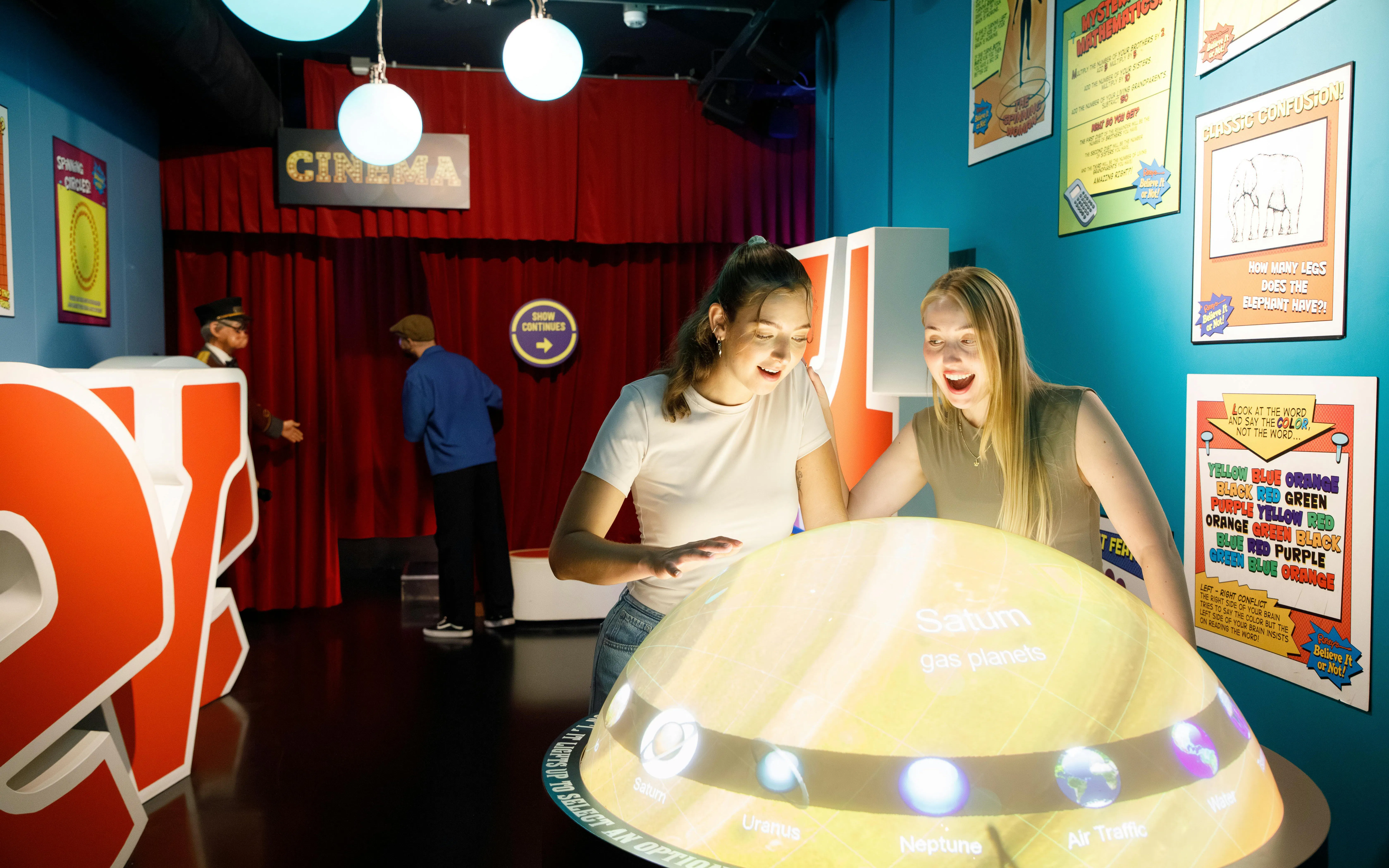 Visitors interact with a glowing planet exhibit at Ripley's Believe It or Not! museum.