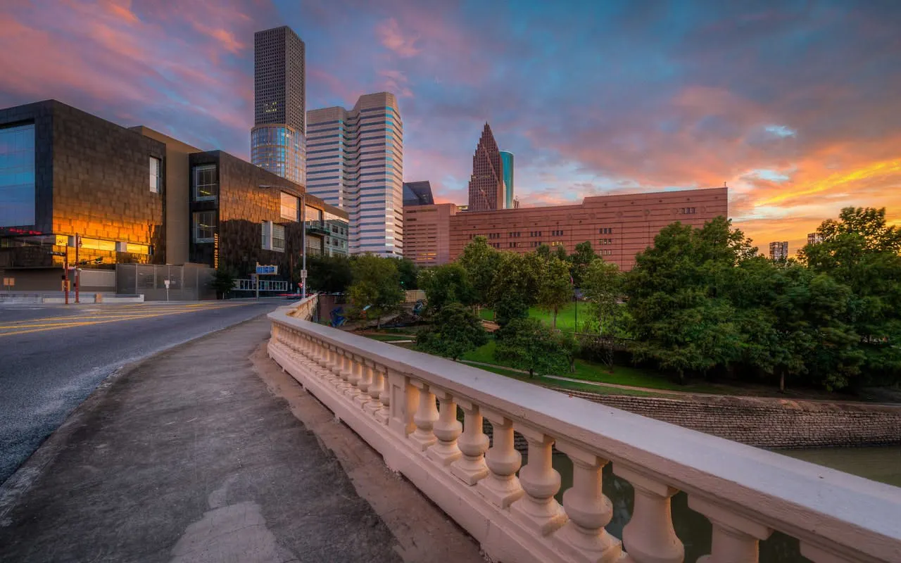 Houston skyline at sunset with modern buildings and a bridge, part of the Haunted Houston exploration game.