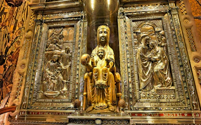 Black Madonna statue at Montserrat Monastery, Spain, surrounded by ornate carvings.