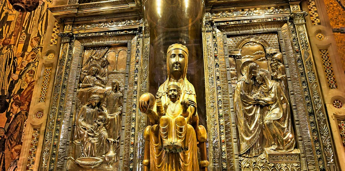 Black Madonna statue at Montserrat Monastery, Spain, surrounded by ornate carvings.