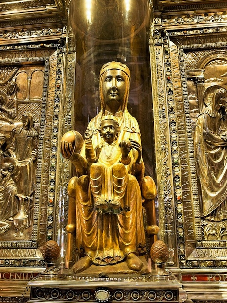 Black Madonna statue at Montserrat Monastery, Spain, surrounded by ornate carvings.