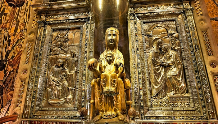 Black Madonna statue at Montserrat Monastery, Spain, surrounded by ornate carvings.