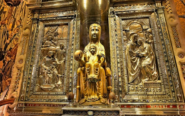 Black Madonna statue at Montserrat Monastery, Spain, surrounded by ornate carvings.
