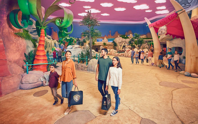 Family exploring Warner Bros. World Abu Dhabi, Yas Island, with park visitors and themed decor.