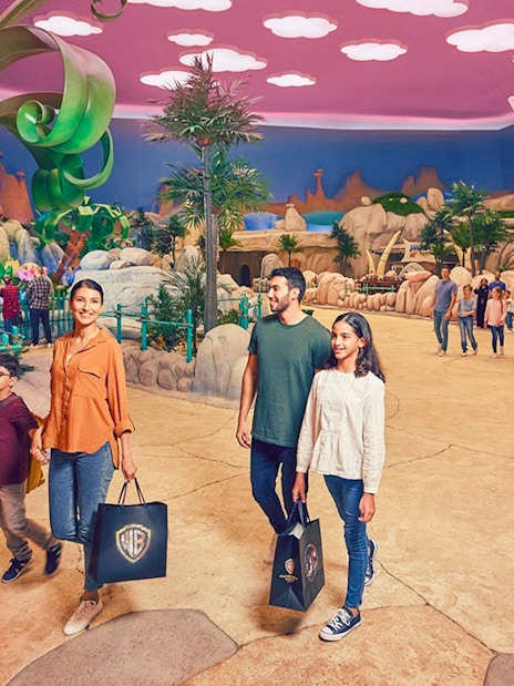 Family exploring Warner Bros. World Abu Dhabi, Yas Island, with park visitors and themed decor.