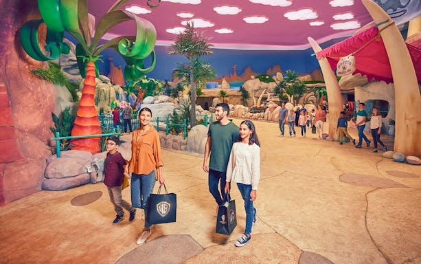 Family exploring Warner Bros. World Abu Dhabi, Yas Island, with park visitors and themed decor.