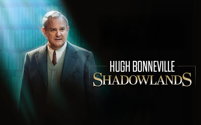 Actor in a suit with "Shadowlands" text on a dark background.