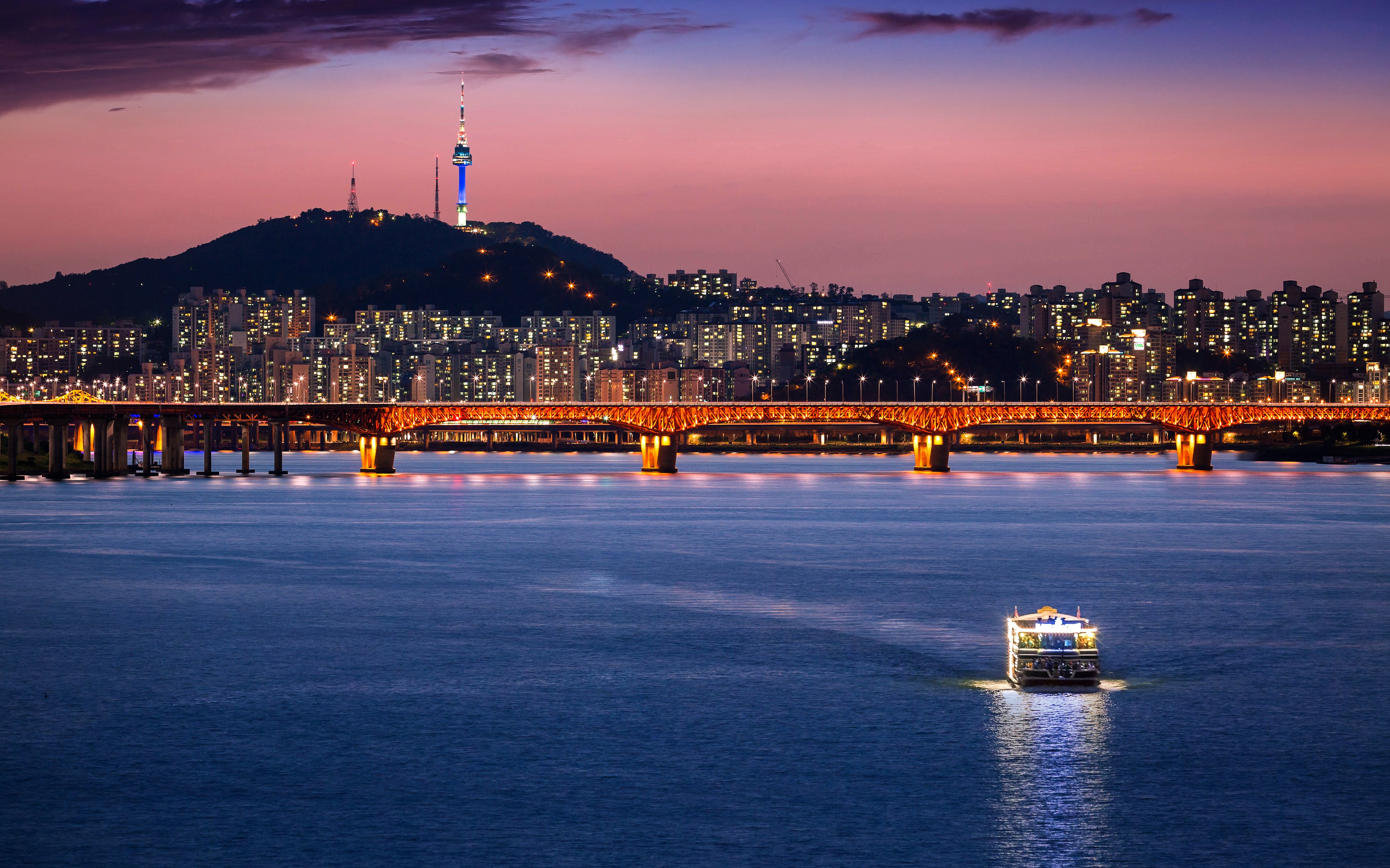 Seoul skyline with illuminated bridge over Han River at dusk, South Korea.