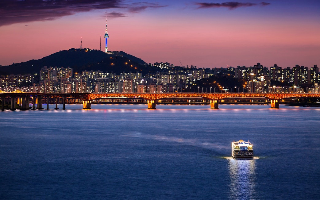 Seoul skyline with illuminated bridge over Han River at dusk, South Korea.