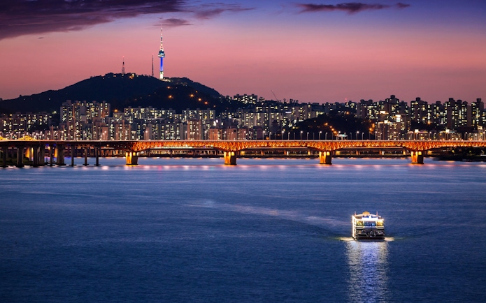 Seoul skyline with illuminated bridge over Han River at dusk, South Korea.