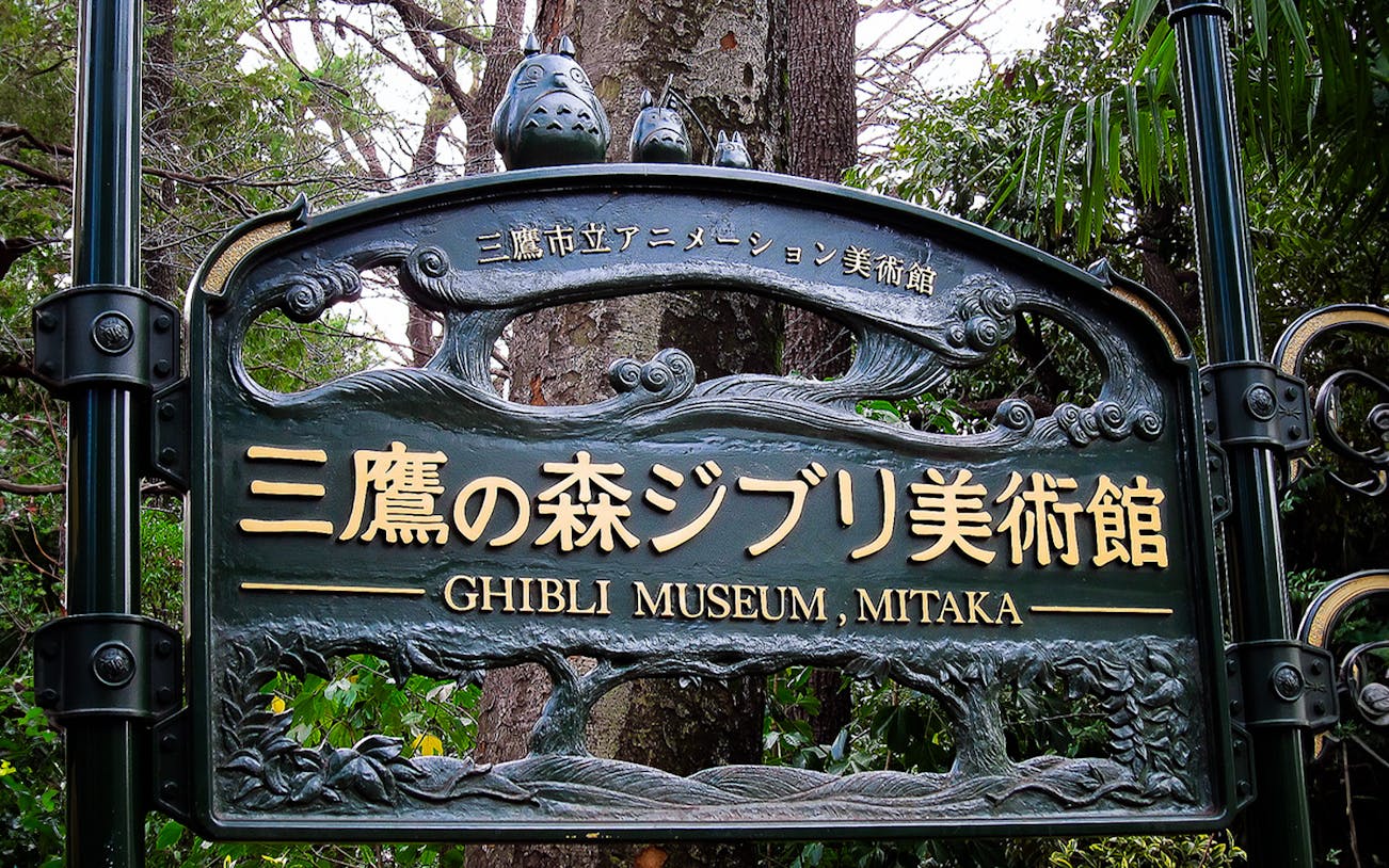 Ghibli Museum entrance sign in Mitaka, Japan, surrounded by trees.