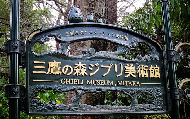 Ghibli Museum entrance sign in Mitaka, Japan, surrounded by trees.