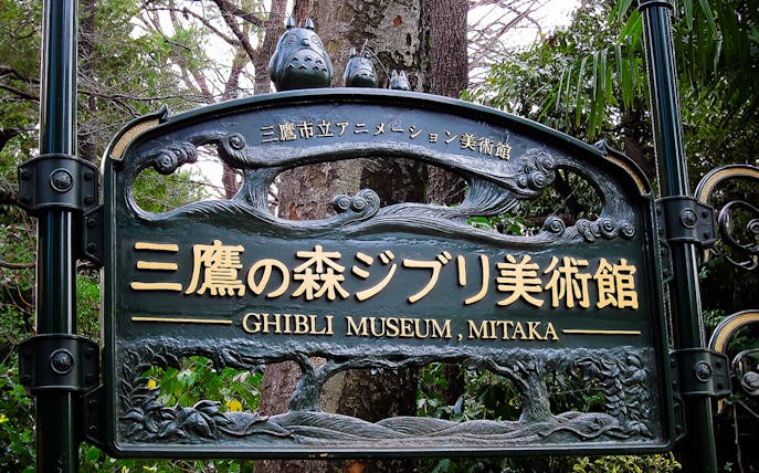 Ghibli Museum entrance sign in Mitaka, Japan, surrounded by trees.