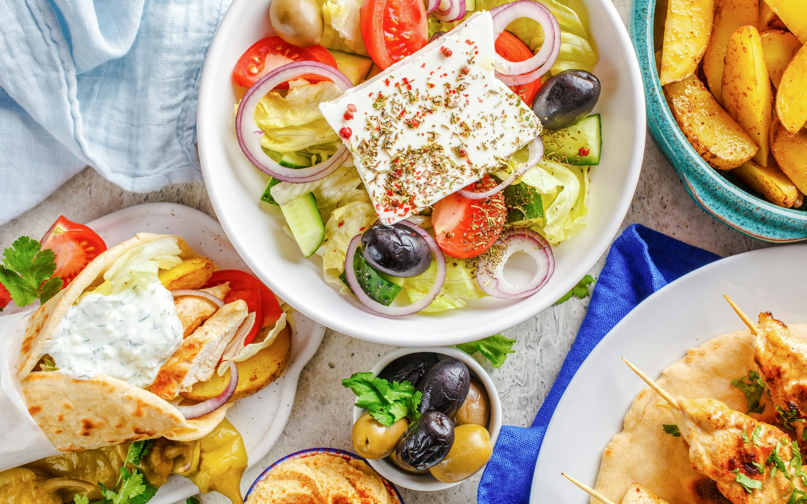 Greek salad, pita with tzatziki, olives, and potato wedges served on a cruise lunch.