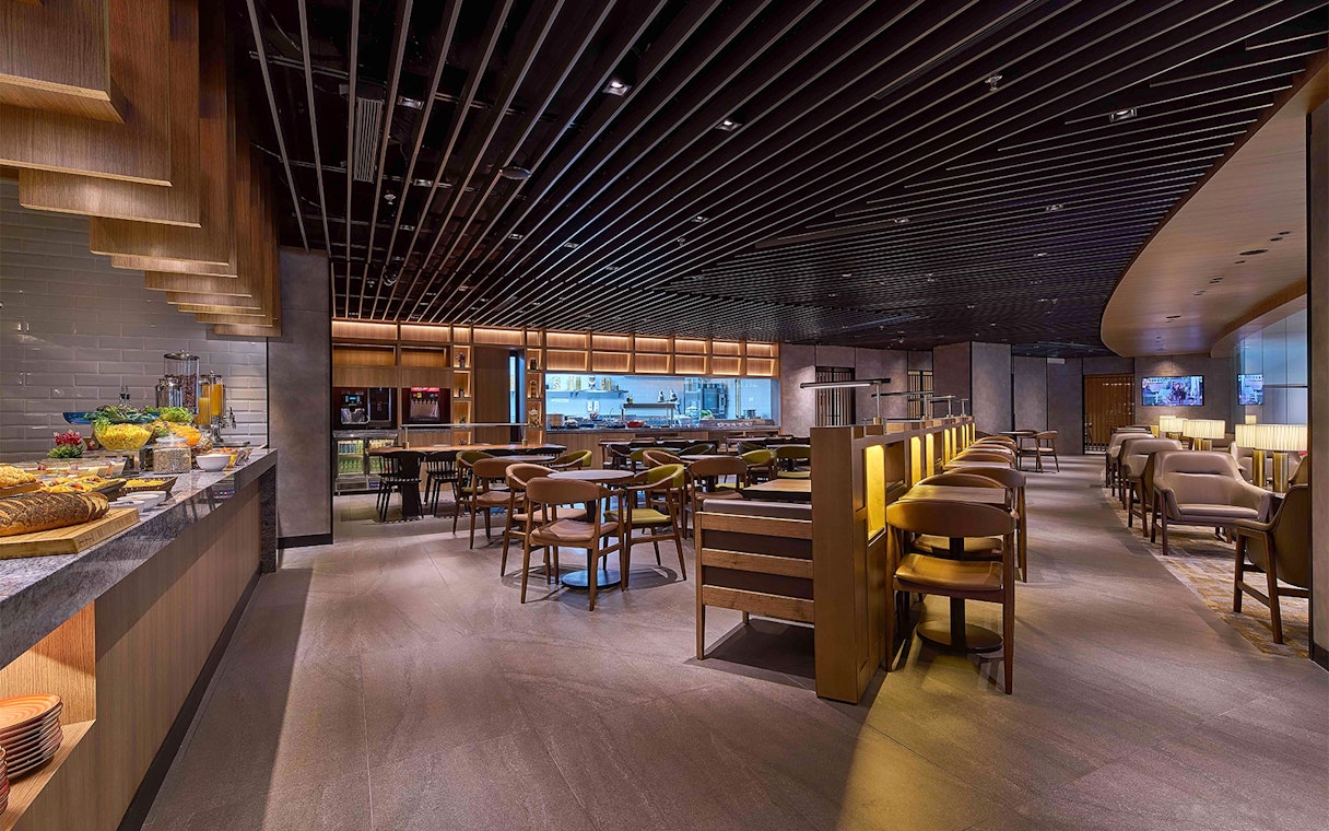 Plaza Premium First lounge seating area with dining tables and buffet counter at Satellite Terminal.