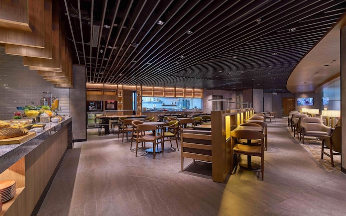 Plaza Premium First lounge seating area with dining tables and buffet counter at Satellite Terminal.