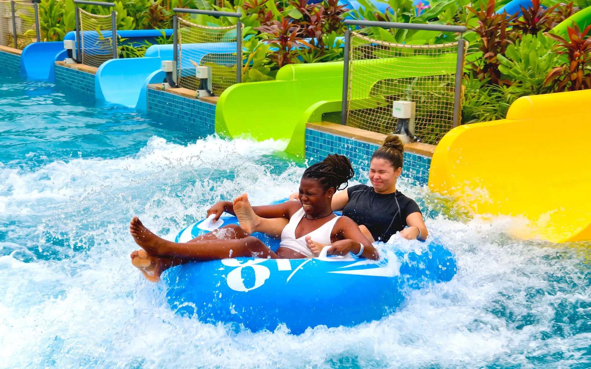 People riding a blue inflatable tube down a water slide at SplashMania Waterpark.
