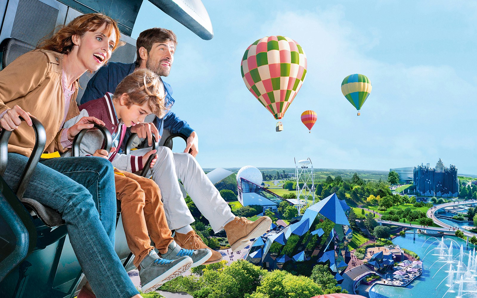 Family enjoying a ride at Futuroscope with hot air balloons in the background.