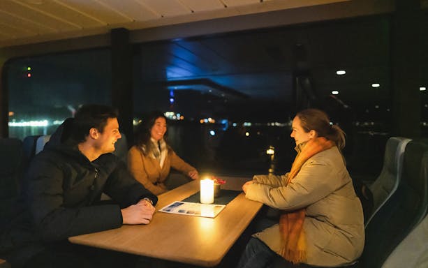 Guests enjoying a candlelit table in a luxurious lounge on a Northern Lights cruise.
