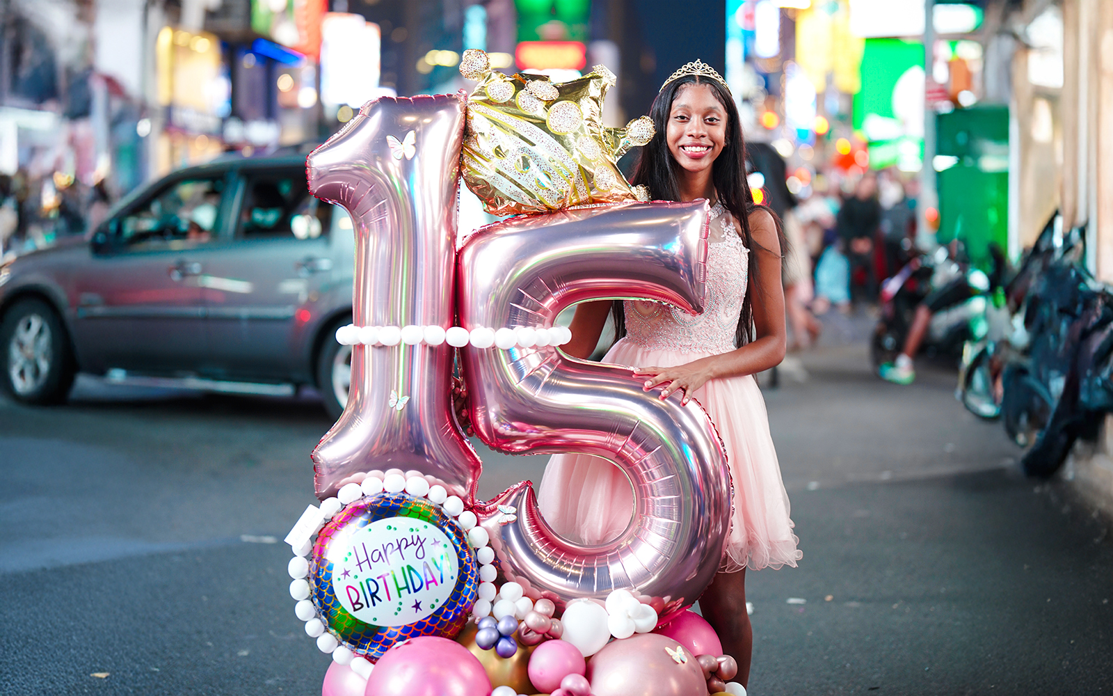 Young woman celebrating 15th birthday with balloons at Times Square, New York City.