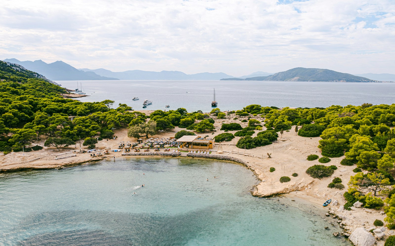 Aerial view of Moni Island, Greece, highlighting the Saronic Gulf's clear waters and lush landscape.