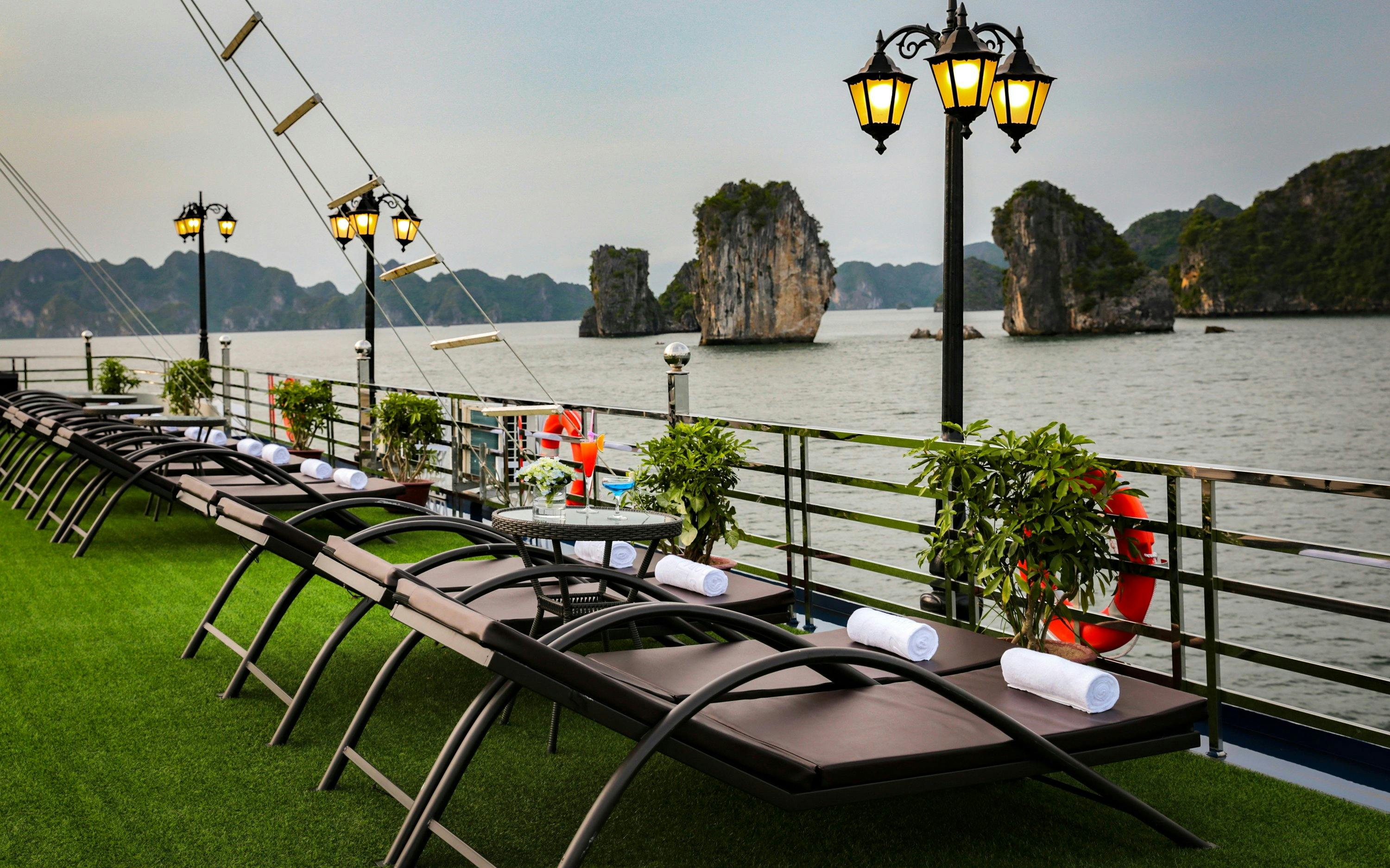 Sun loungers on a cruise deck overlooking limestone islands in Lan Ha Bay.