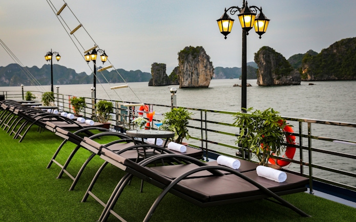 Sun loungers on a cruise deck overlooking limestone islands in Lan Ha Bay.