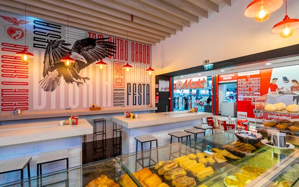 Benfica stadium cafe interior with pastries and eagle mural.