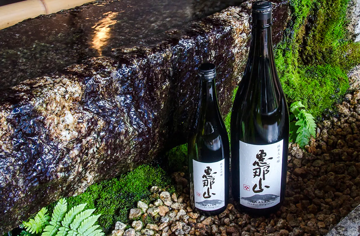 Sake bottles at Hazama Brewery, Nakatsugawa, surrounded by moss and stones.