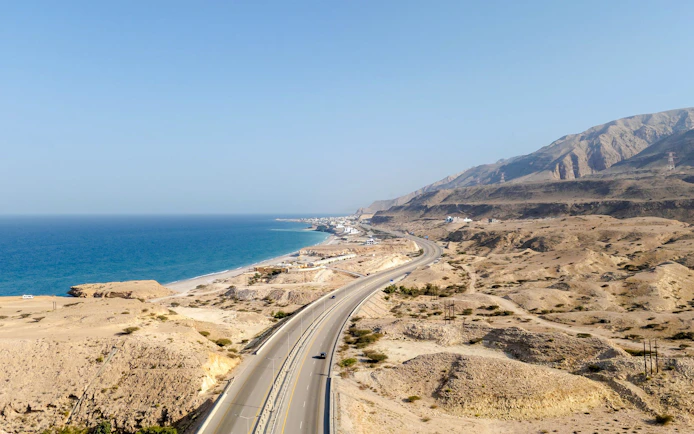 Highway along the coastline of Muscat with mountains and sea in view.