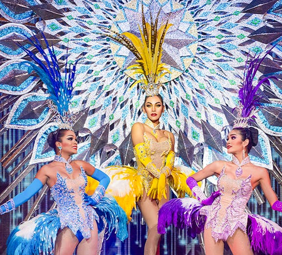 Performers in vibrant costumes on stage at Alcazar Cabaret, Pattaya, Thailand.