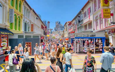 Crowded street in Chinatown, Singapore with colorful shophouses and tourists exploring.
