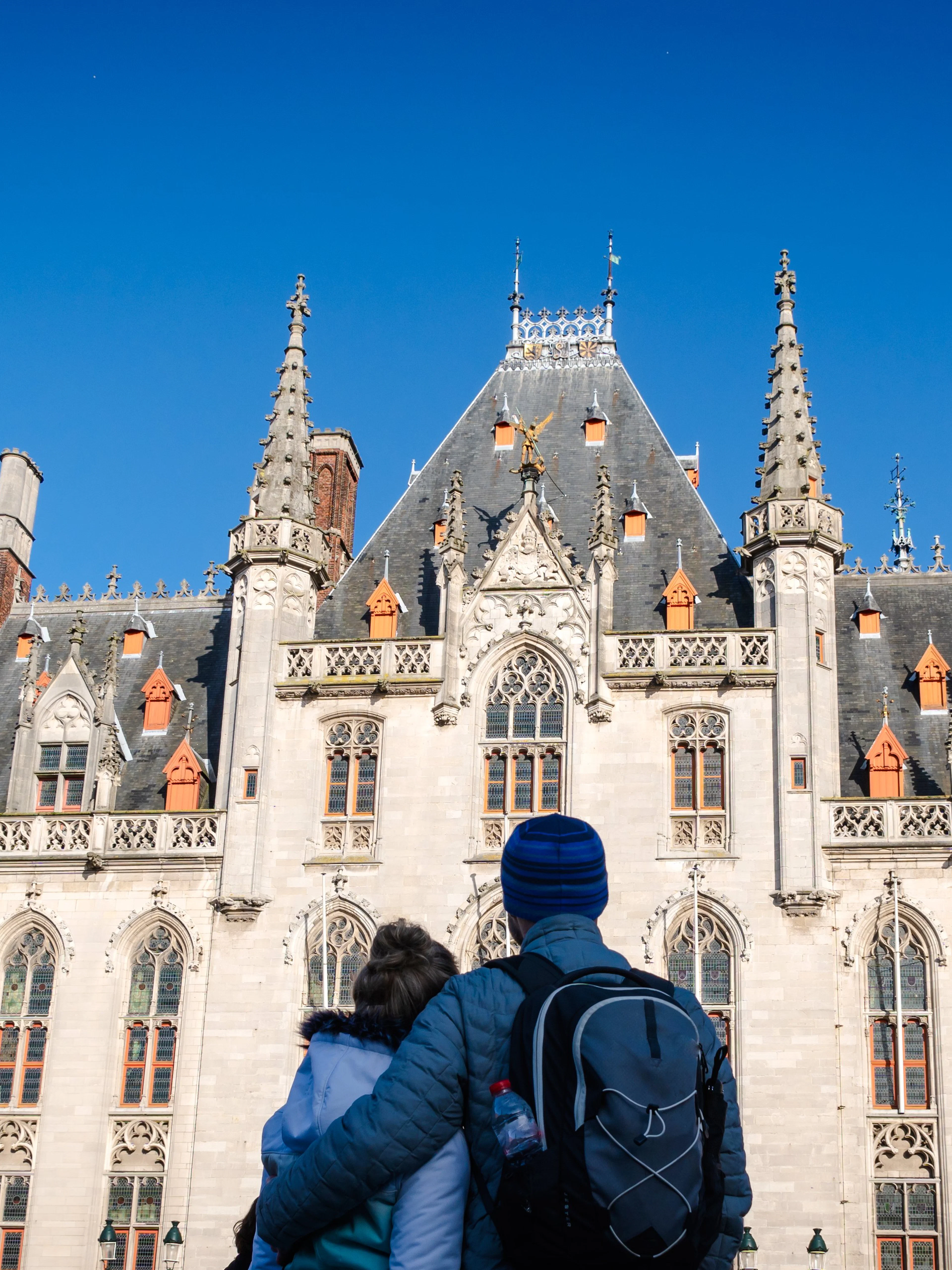 Couple admiring the historic architecture of Bruges City Hall.