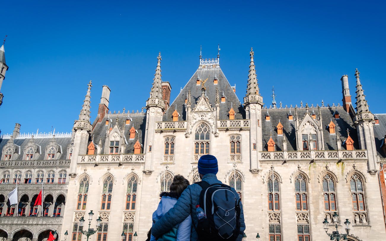 Couple admiring the historic architecture of Bruges City Hall.