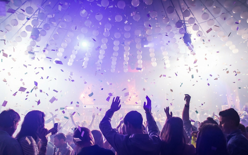 Crowd dancing under confetti at Mandala Nightclub in Cancun.