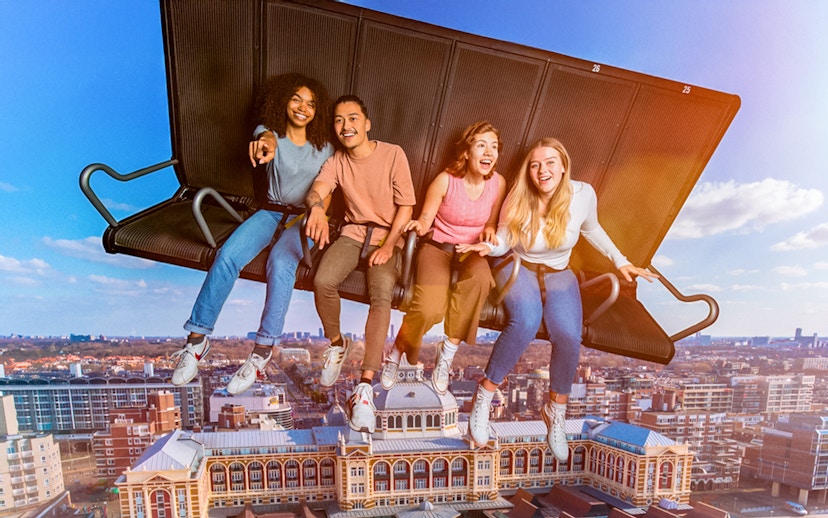 Tourists experiencing 5D ride at This Is Holland, flying over Amsterdam cityscape.