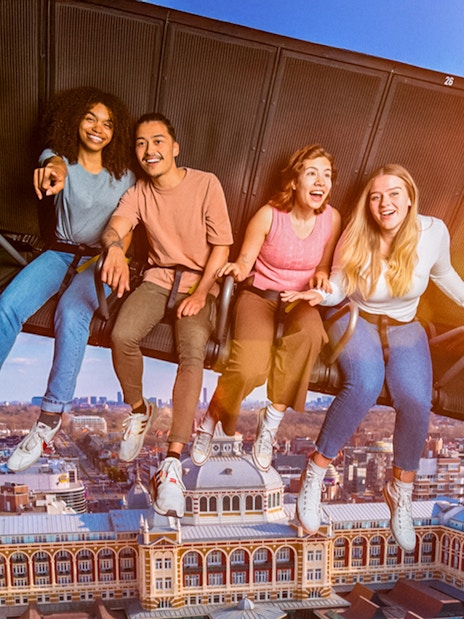 Tourists experiencing 5D ride at This Is Holland, flying over Amsterdam cityscape.