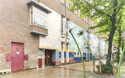 Anne Frank House exterior with colorful mural and large flower sculptures in Amsterdam.