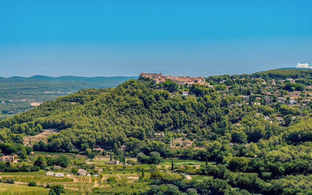 Hilltop village surrounded by vineyards in Bandol, France, under a clear blue sky.