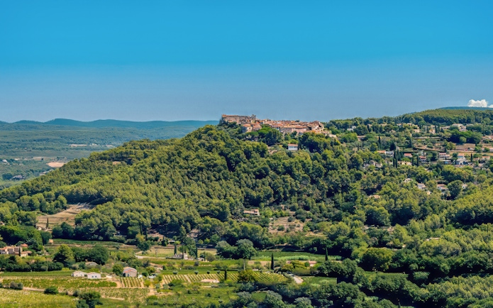 Hilltop village surrounded by vineyards in Bandol, France, under a clear blue sky.