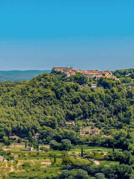 Hilltop village surrounded by vineyards in Bandol, France, under a clear blue sky.