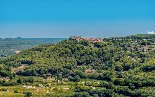 Hilltop village surrounded by vineyards in Bandol, France, under a clear blue sky.