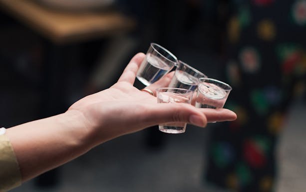 Hand holding shot glasses during Vodka and Liqueurs Tour in Krakow.