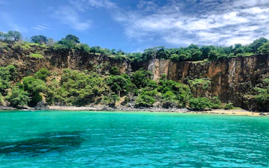Cliffs and turquoise waters at Sancho Beach, part of the Noronha Boat Tour from Sao Paulo.