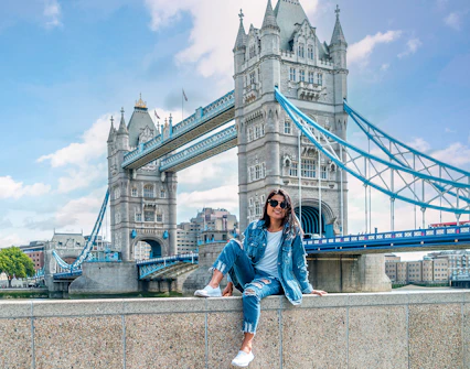Tower Bridge over River Thames in London with a person sitting on a wall, part of Go City tour.