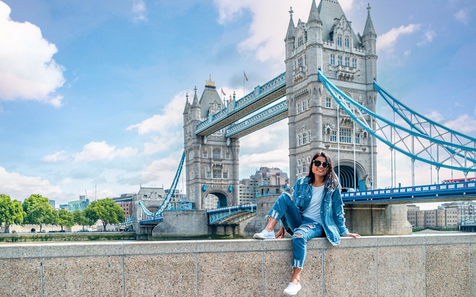 Tower Bridge over River Thames in London with a person sitting on a wall, part of Go City tour.