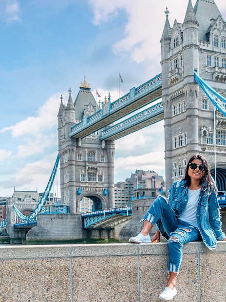 Tower Bridge over River Thames in London with a person sitting on a wall, part of Go City tour.